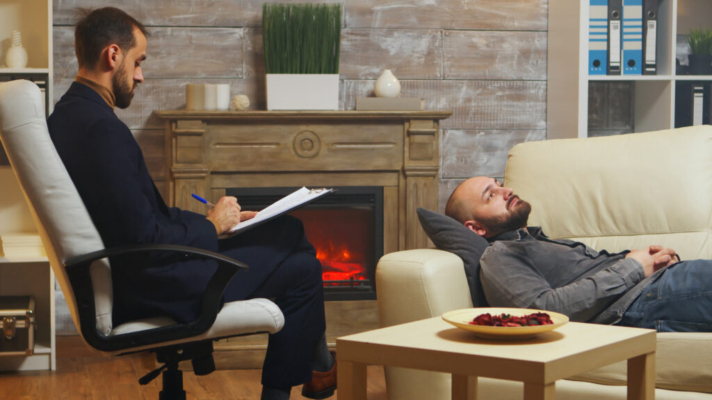 bearded man laying down on couch at couple therapy